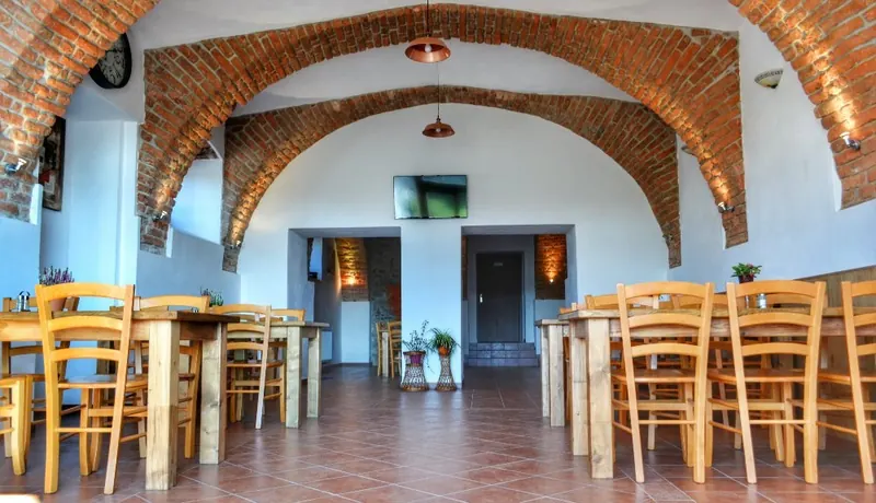Bar pod cihlovou klenbou se stoly z masivu