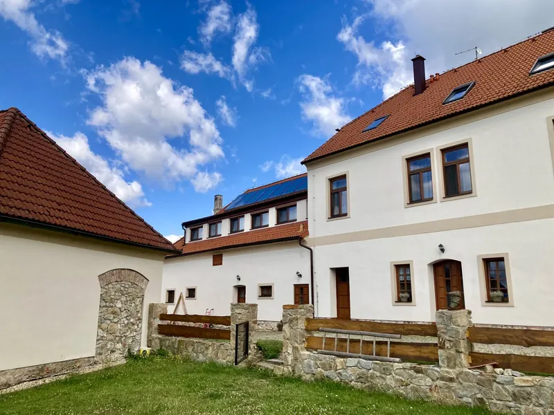 Dvůr penzionu s kamennou zídkou a bílými budovami